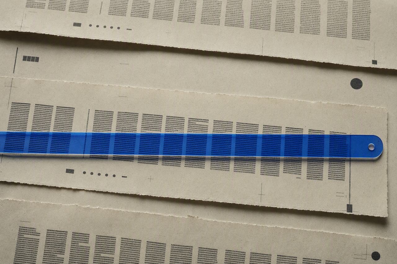 A blue reading ruler crossing layered strips of abstract newsprint, revealing one focused line.